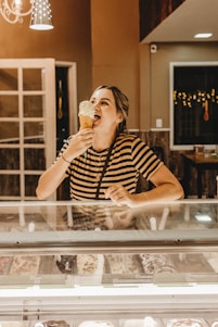A colorful display of assorted ice cream cones and sundaes with happy customers enjoying them in a bright, cheerful shop.