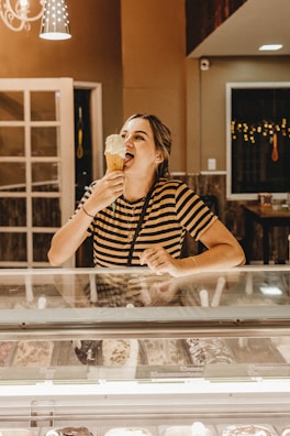 A smiling customer enjoying a scoop of creamy ice cream at the counter.
