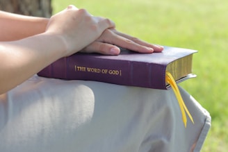a woman's hand resting on a book that says the word of god