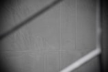 Gray tiles with visible grout lines form a geometric pattern, intersected by a soft, diagonal shadow.