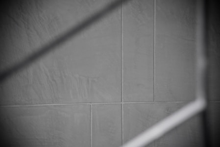 Gray tiles with visible grout lines form a geometric pattern, intersected by a soft, diagonal shadow.