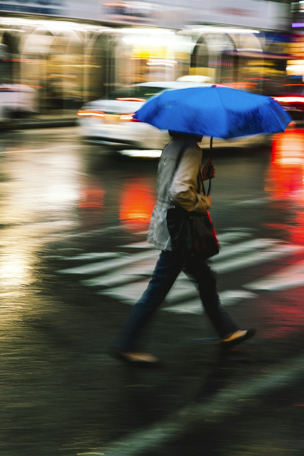 person walking on pedestrian lane while holding umbrella