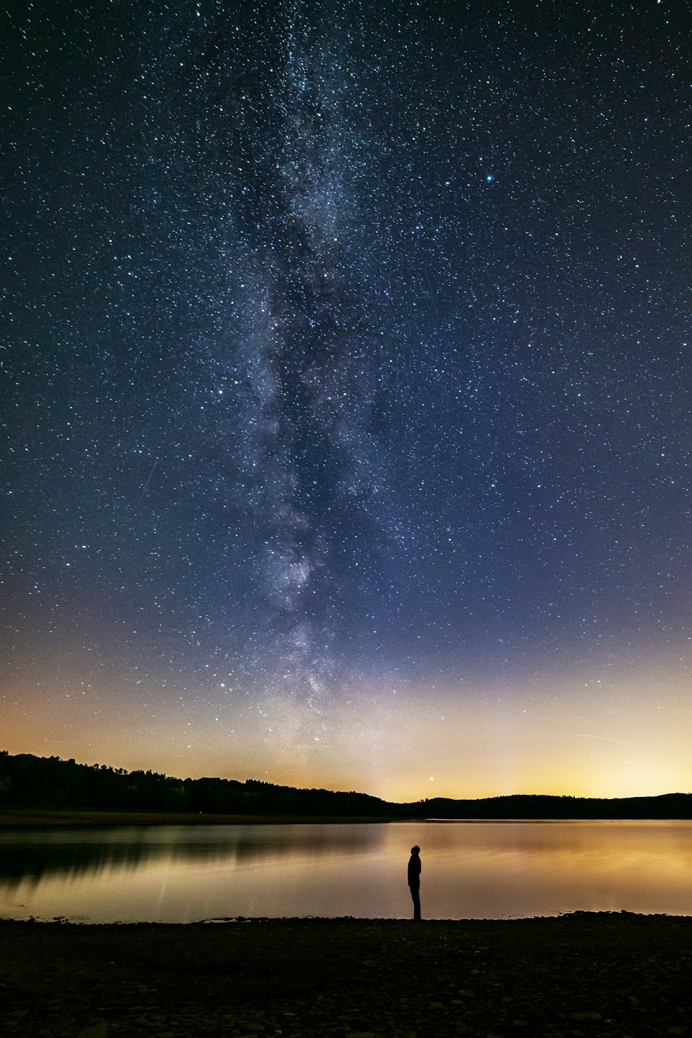 a person standing on a beach under a night sky