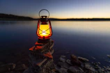 turned-on gas lamp on rock beside sea
