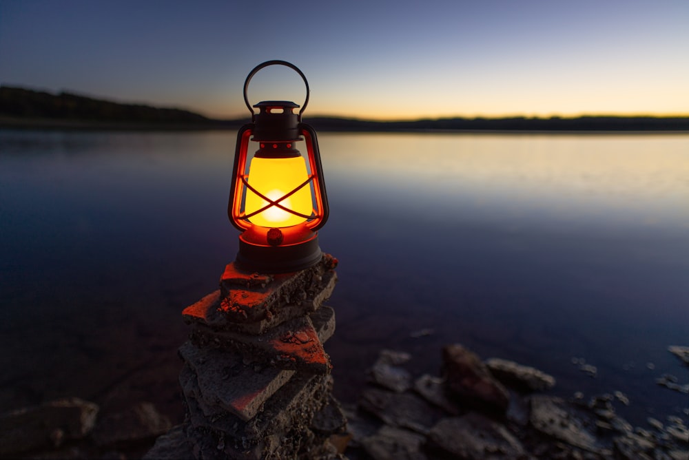 turned-on gas lamp on rock beside sea