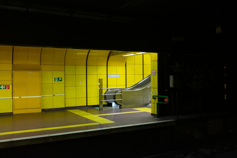 a subway station with a yellow wall and stairs