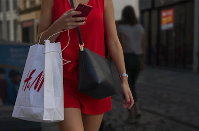 A stylish woman happily completing her purchase on a smartphone with red and black accents.