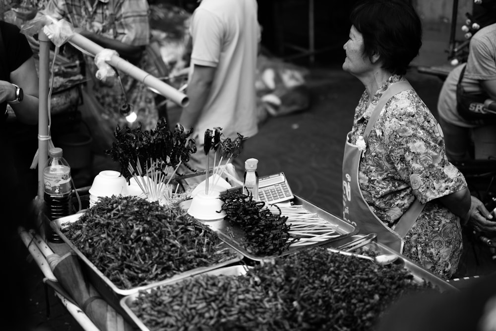 foto em tons de cinza de pessoas perto de flores