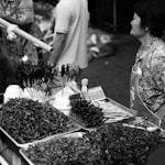 grayscale photo of people near flowers