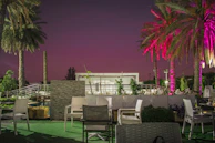 Outdoor seating area with palm trees and soft evening lighting at a hotel.