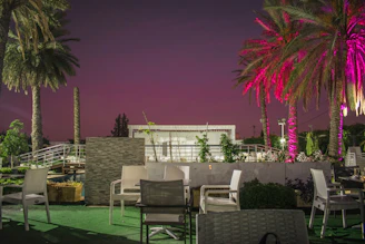 Outdoor seating area with palm trees and soft evening lighting at a hotel.