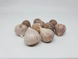 Fresh white garlic bulbs with papery skins resting on burlap.
