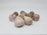 A cluster of garlic bulbs displayed on a clean, light-colored surface. The garlic bulbs have a natural, papery outer skin with a mix of off-white and purple hues.