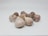A cluster of garlic bulbs displayed on a clean, light-colored surface. The garlic bulbs have a natural, papery outer skin with a mix of off-white and purple hues.