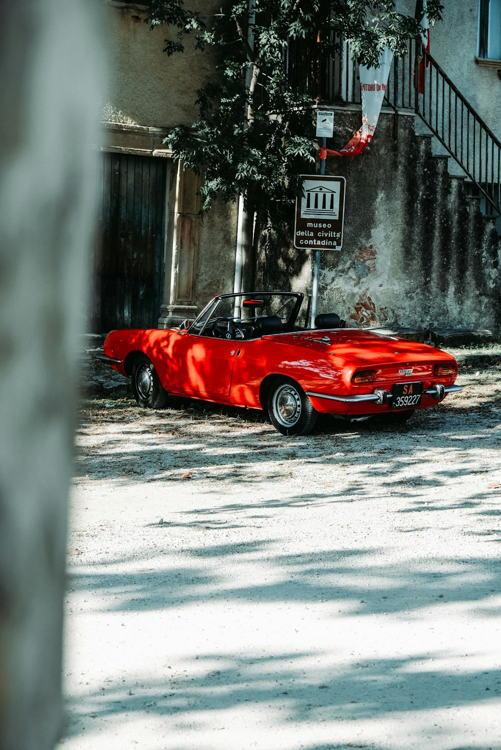 red convertible coupe parked beside building