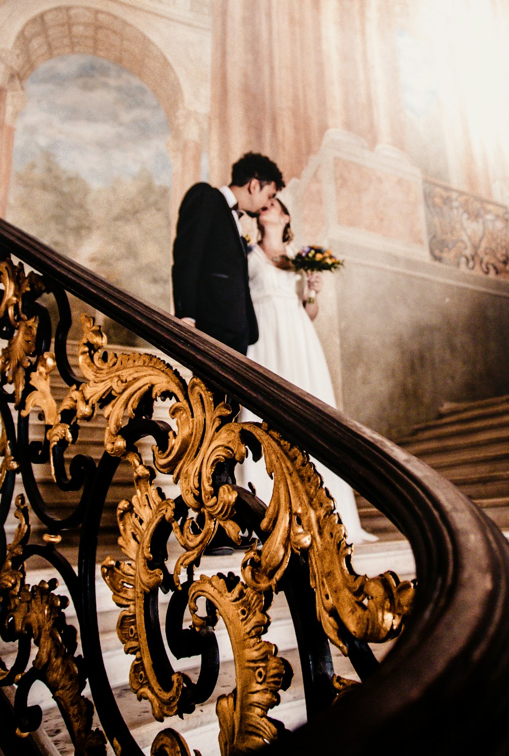 man and woman kissing while standing on stairs