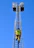 A firefighter is climbing a tall metal ladder on a fire truck, reaching towards two platforms against a clear blue sky. The firefighter is wearing protective gear, including a helmet and high-visibility jacket.