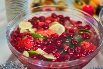 Colorful fruit tea with slices of fresh tropical fruits and natural sweeteners in a clear cup