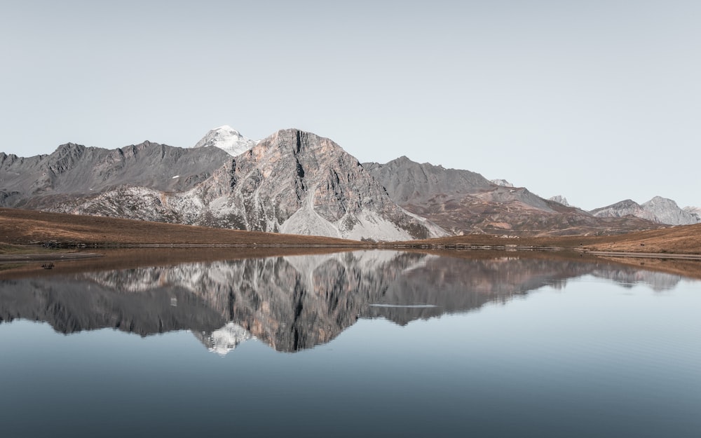 Montagna grigia attraverso lo specchio d'acqua