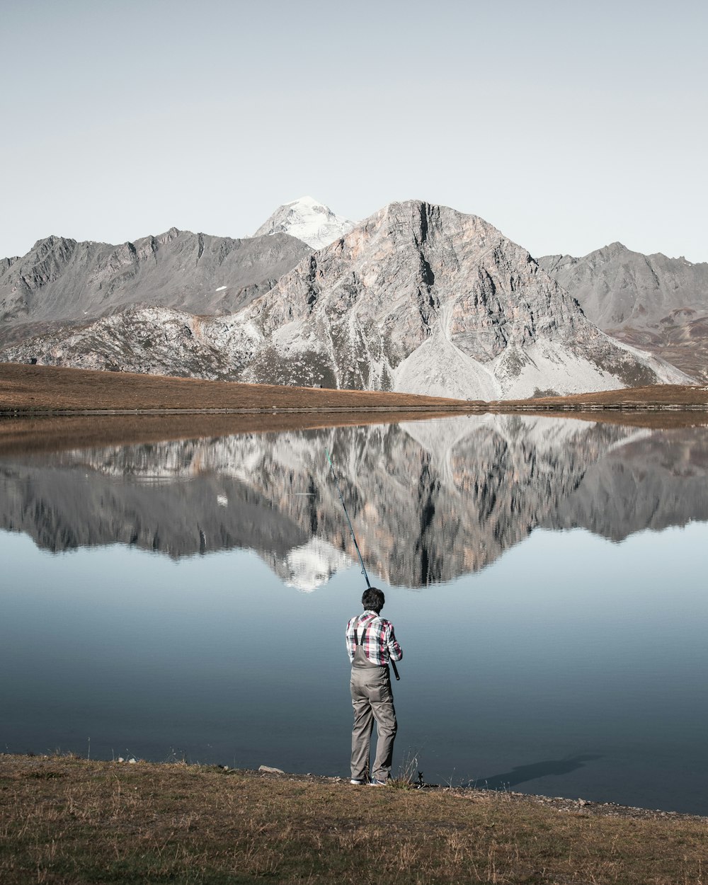 man fishing on calm water at daytime