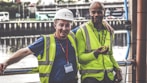 selective focus photography of two men standing side by side wearing green reflective vests