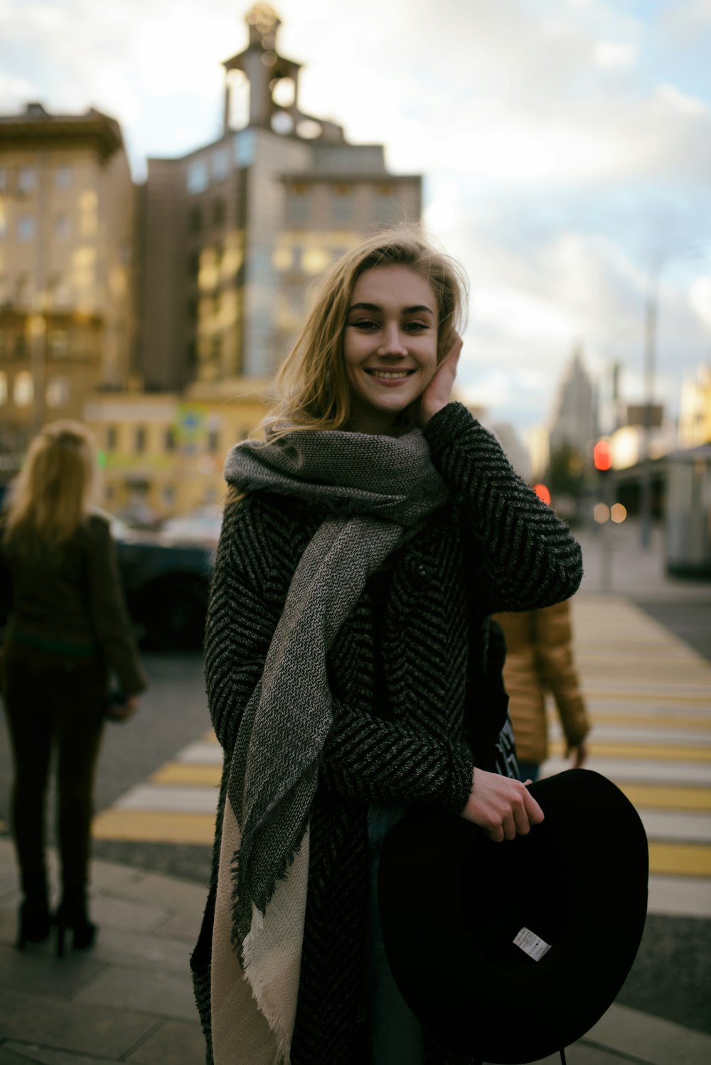 selective focus photography of smiling woman wearing scarf beside pedestrian lane