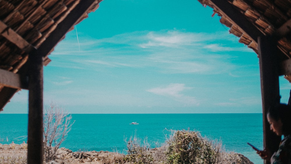 person using smartphone under shed near sea