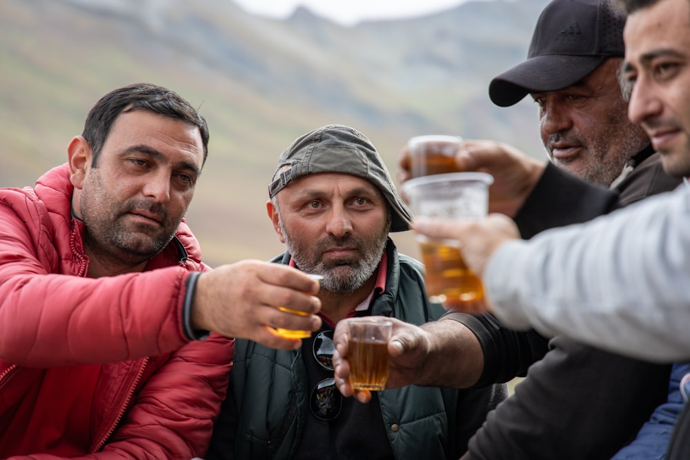 selective focus photography of men holding filled cups during daytime