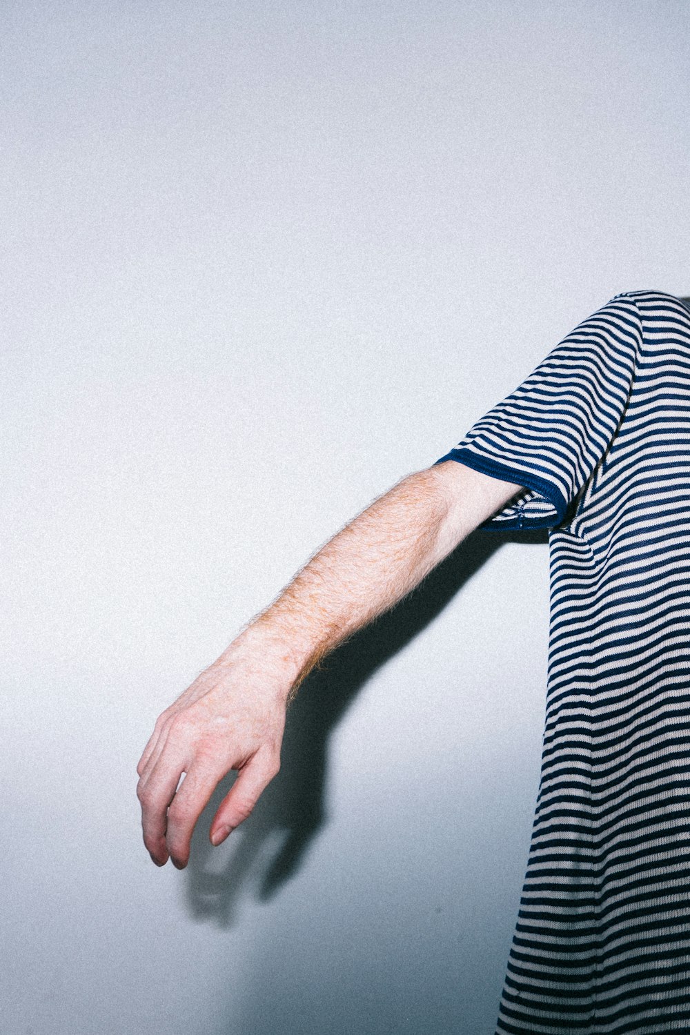 person wearing black and white striped t-shirt standing near white wall