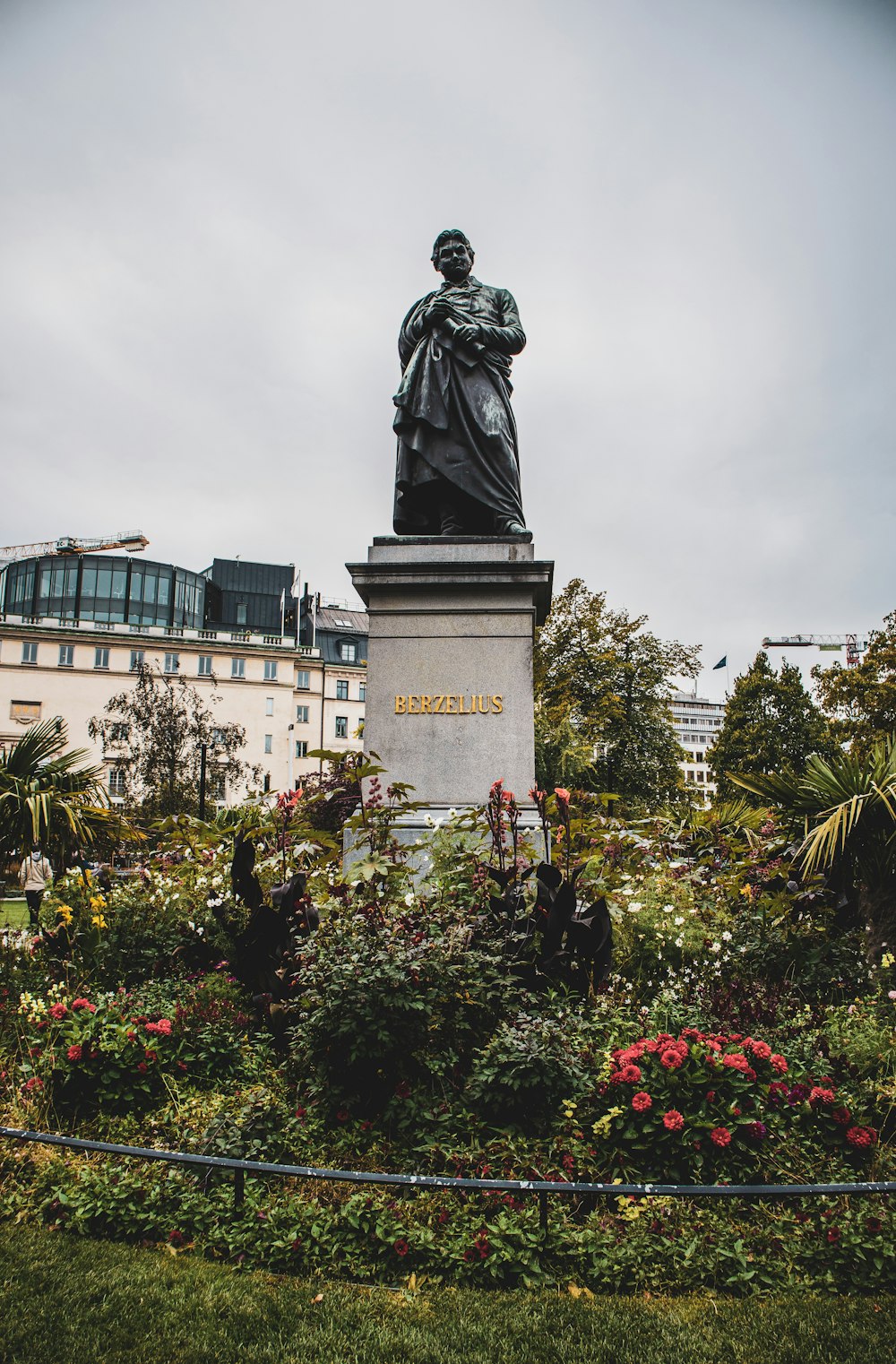 gray concrete man statue near flowers during daytime