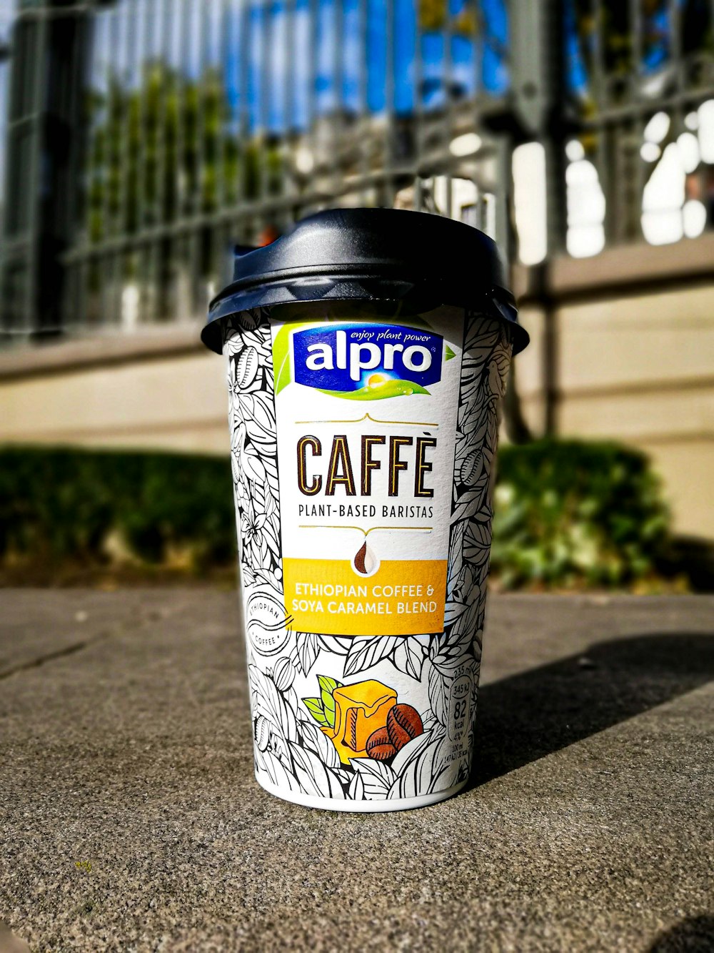 Alpro caffee coffee cup with lid on concrete pavement