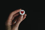 person holding red and white hear button