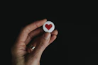 person holding red and white hear button