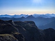 A panoramic view from a summit showing layers of mountains fading into the horizon.