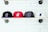 Four baseball caps are neatly lined on a wooden shelf against a white brick wall. Each cap features an embroidered bear logo. The caps are in black, red, dark gray, and white colors.