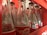 Rows of empty, clear glass bottles with red and white labels are neatly arranged in a red plastic crate. The bottles are positioned closely together, showcasing a familiar logo associated with a popular soft drink. The inner surfaces of the crate have slots that hold the bottles securely.