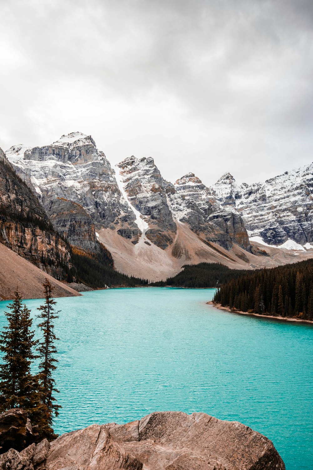 body of water near trees and glacier mountains during day