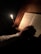 A close-up of a person reading a book with a candle lit beside them.