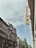 A street view featuring classic European architecture with ornate facades and a tall, narrow sign reading 'Otthon' attached to the side of a building. The sky is overcast with a hint of blue peeking through.