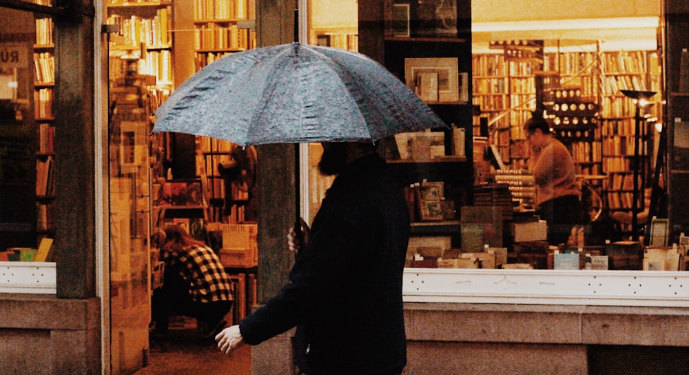 man holds umbrella near store