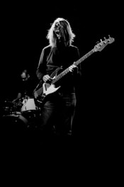 man playing electric bass guitar in grayscale photography
