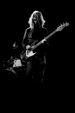 man playing electric bass guitar in grayscale photography
