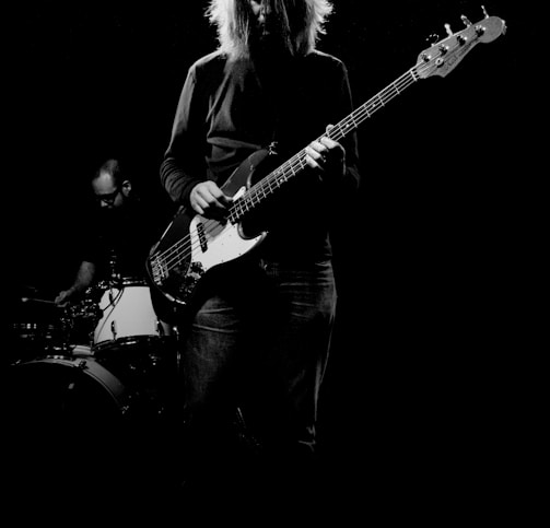 man playing electric bass guitar in grayscale photography