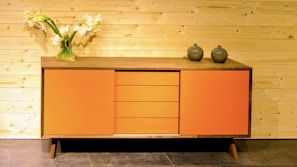 A stylish console storage unit with clean lines and subtle red accents matching the brand palette.