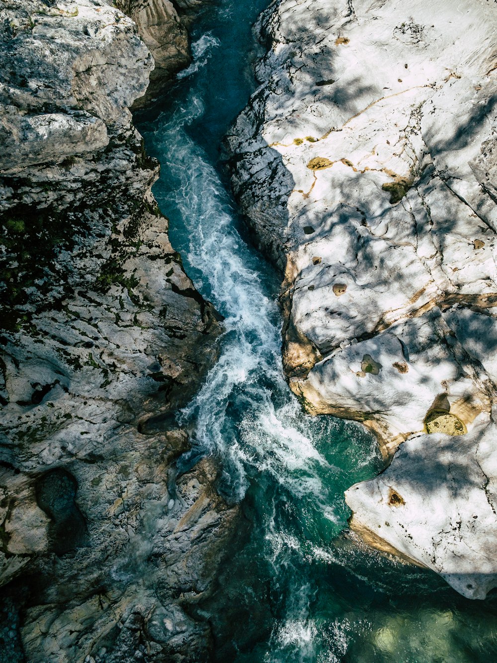 an aerial view of a river flowing between two rocks