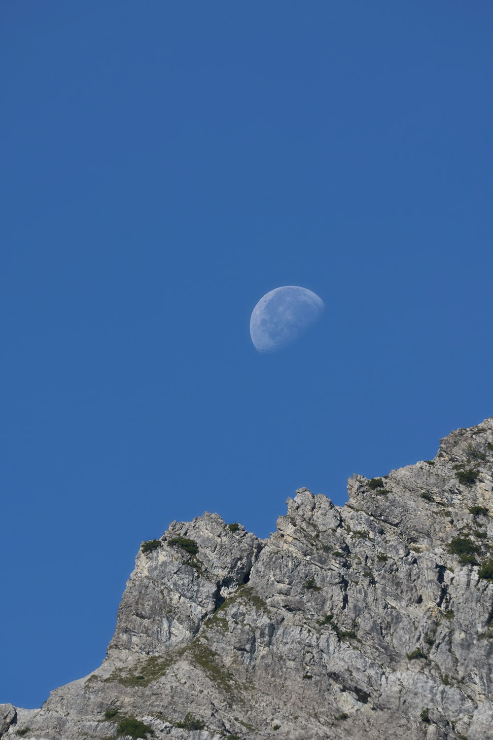 rocky hill viewing half moon during daytime