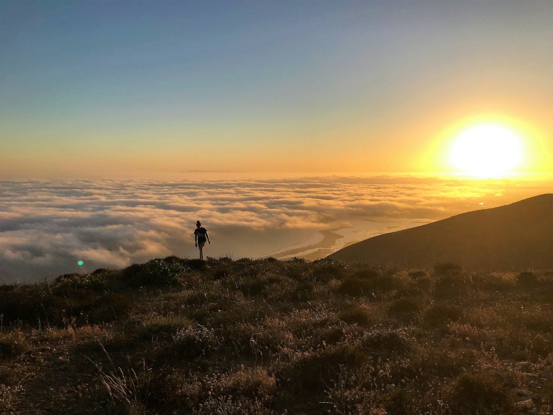 silhouette of standing person on cliff