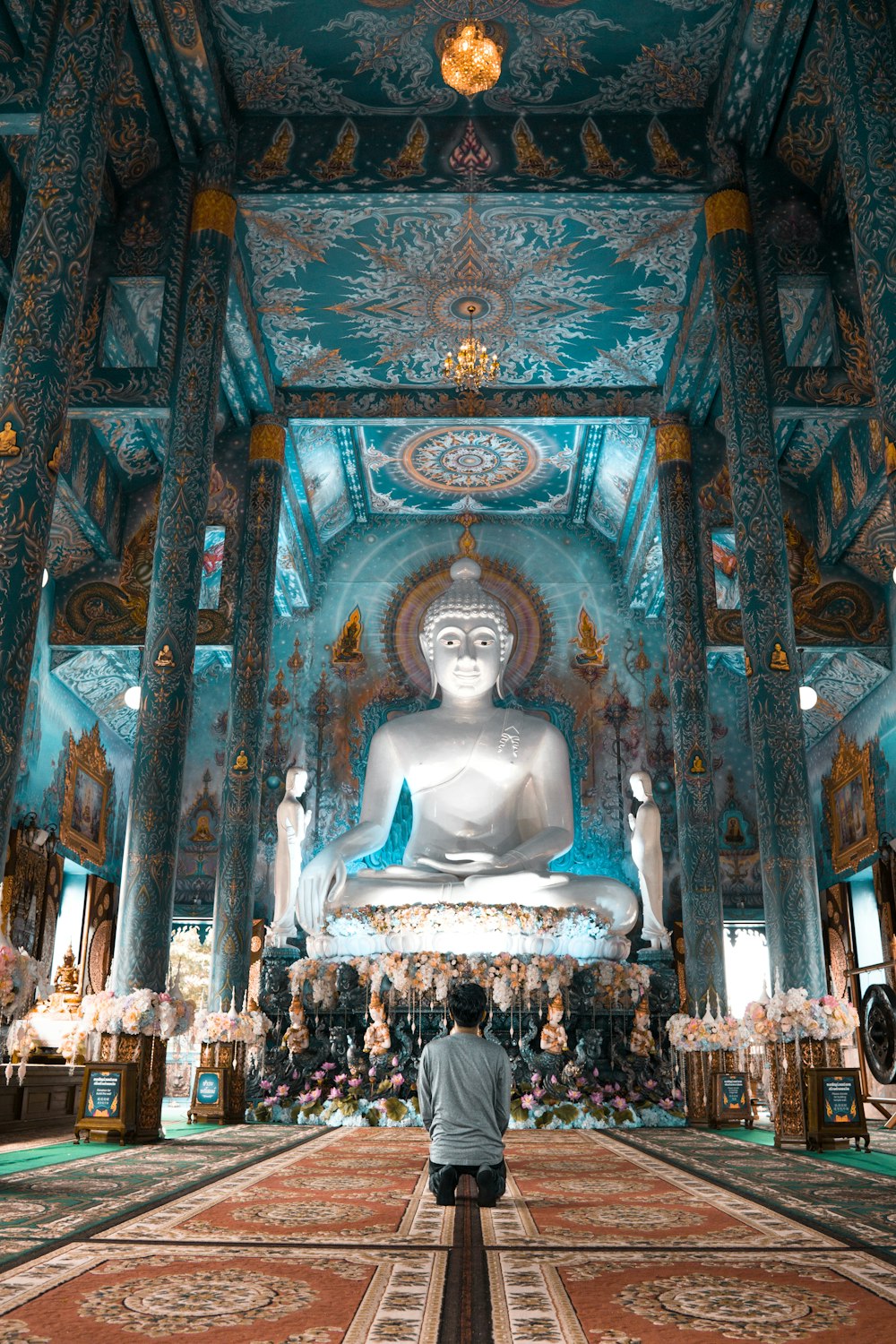 person kneels near Buddha