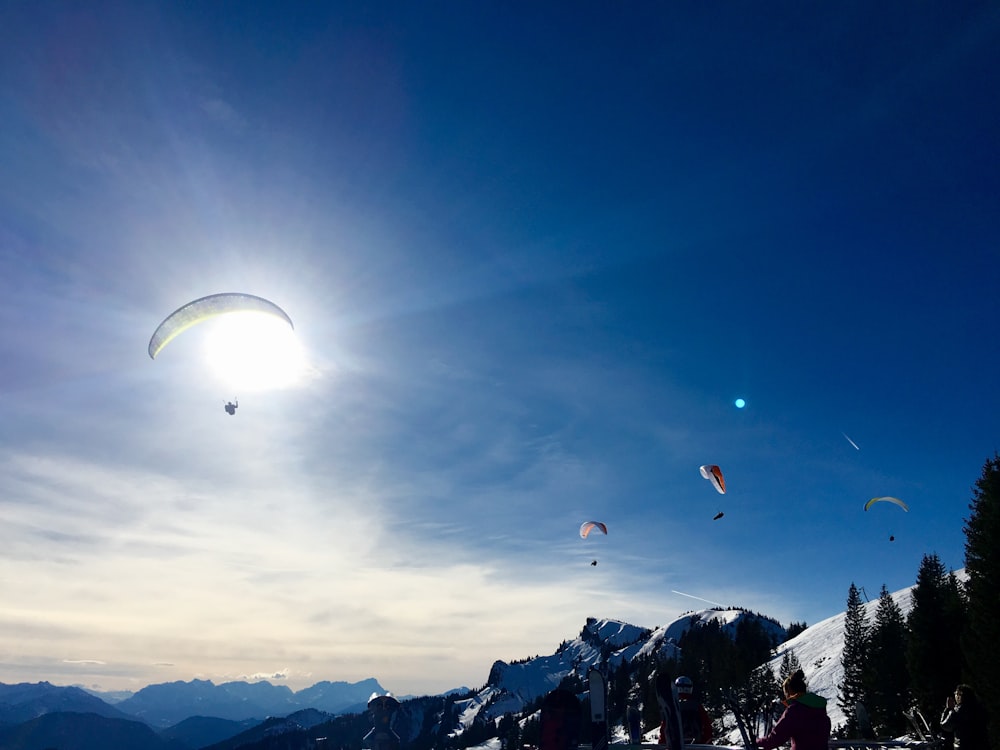 people paragliding above mountain under blue and white skies during daytime