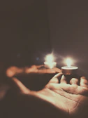 Close-up of hands performing a gentle reiki session with soft candles in the background.